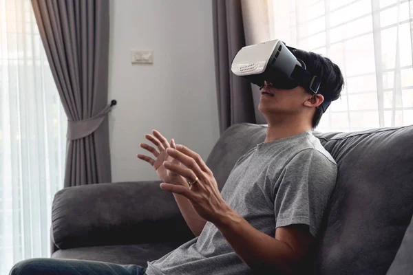 Un hombre alegre sentado en el sofá y el uso de la realidad virtual 3D g — Foto de Stock