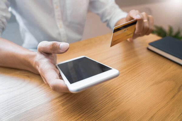 Hand of man in casual shirt paying with credit card and using sm