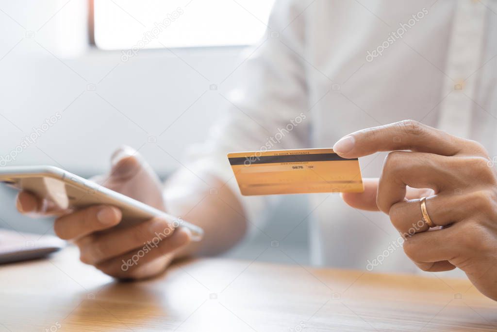 Hand of man in casual shirt paying with credit card and using sm
