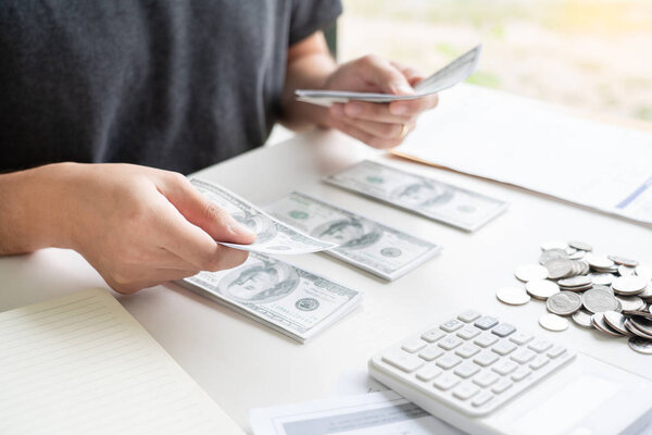 Человек, использующий калькулятор и рассчитывающий квитанции по счетам за дом
