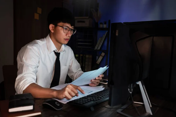 年轻的忧心忡忡的亚洲人工作到很晚 晚上在黑暗的办公室 深夜工作或学习概念 在计算机前专心认真地工作 — 图库照片