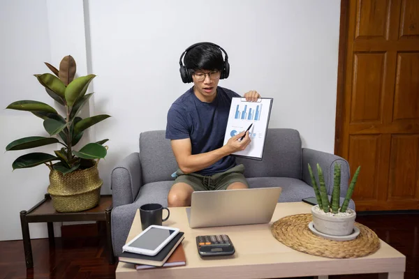 Young man calling with customer on the sofa or speak talk on video call with diverse multiracial colleagues on online briefing, conference with coworkers on modern laptop at home