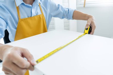 Erkeklerin elinde, evi yenilemek için esnek cetvelle ölçülen bir mezura var. onarım, mimari ve ev yenileme ve konsept