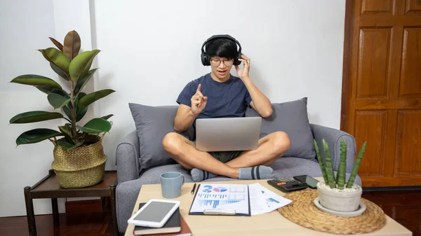 Young man calling with customer on the sofa or speak talk on video call with diverse multiracial colleagues on online briefing, conference with coworkers on modern laptop at home