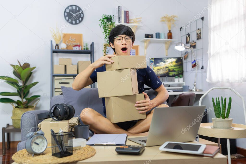 start up small business asian man young entrepreneur preparing parcels packing cardboard box for delivery process for send order to customer at home office, Online marketing