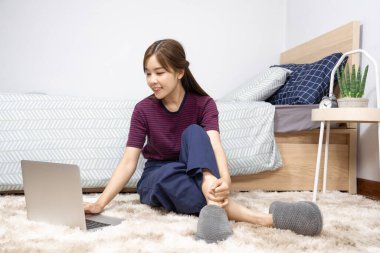Yatakta dizüstü bilgisayar kullanan Asyalı kadın evde çalışmaktan, uzaktan çalışmaktan ya da evden çalışmaktan keyif alıyor..
