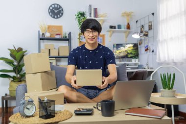 Asyalı erkek işyeri sahibi ya da internet üzerinden merchance satan ve müşteriye sipariş göndermek için ürün paketleme karton paket kutusu hazırlayan, online alışveriş, iş sahibi, teslimat konsepti