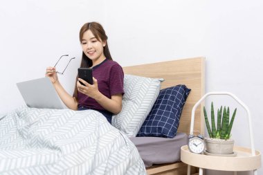 Evde, sosyal medyada akıllı telefon veya tabletle çalışan Asyalı kadın, evde kalıp karantina veya uzak çalışma ve yaratıcılık kavramı