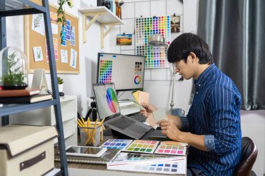 Asyalı erkek Mimarı veya grafik tasarımcısı yenileme, Yaratıcı Meslek Stüdyosu konsepti için renk ekran grafikleri için bir desen seçimi örnekleri tasarlıyor