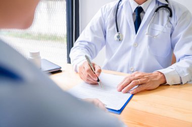 Çekici Asyalı erkek doktor klinikteki bir kadın hastaya tavsiye ve tıbbi danışmanlık yapıyor.