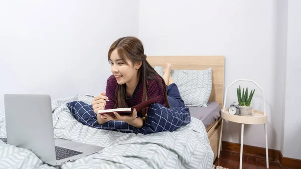 Asian woman using laptop computer on the bed and enjoy working at home, Working remotely or Work from home and concept.