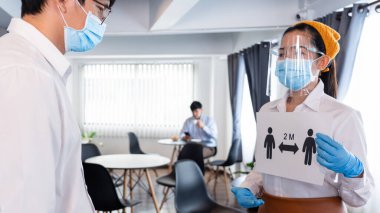 Garson, restoranda salgın Covid-19 veya Coronavirus salgınının yayılmasını önlemek için müşterilere olan sosyal mesafeyi açıklayan bir tabela tutuyordu..
