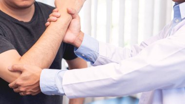 Fizyoterapist çalışma konsepti, doktor ve hastanın acı çekmesi veya klinikte omuz veya dirsek ağrısından muayene olan kayropraktik uzmanı.