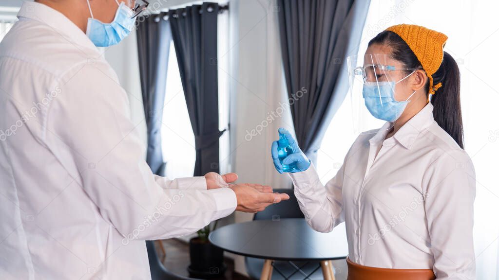 Waitress staff using Disinfectant Spray alcohol or gel to prevent the spread of pandemic Covid-19 or Coronavirus to customer hands at restaurant, new normal concept