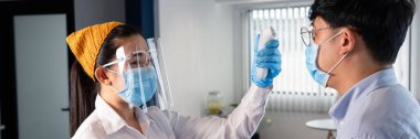 Garson maske takıyor ve alıcıyla müşterinin vücut ısısını kontrol ediyor Coronavirus 'tan korumak için restorana girmeden önce Tıbbi Dijital Kızılötesi Termometre kullanıyor (COVID-19).