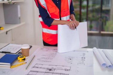 Yetişkin profesyonel, ayrıntılı ve güvenlik üzerine odaklanarak mimari planlar analiz ederek, projenin başarıyla tamamlanması için yenilikçi yapı çözümlerini teşvik eder.