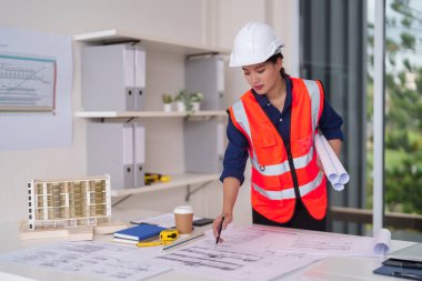 Yetişkin Asyalı mimar kompleks planlar üzerinde çalışıyor model kentsel gelişim inşa ediyor. Mühendislik tasarımı gelecekteki yapıları planlıyor. Konsantrasyon mesleğine odaklan.