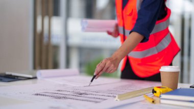 Profesyonel mimar, bir inşaat projesinin ayrıntılı planlarını inceliyor. Bu kendini adamış mühendis, iş yerinde kalite ve güvenliği sağlayacak tasarımlar yapmayı özenle planlıyor.