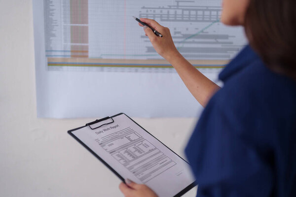 Взрослый архитектор анализирует проектные данные на большой диаграмме. Руки держат ежедневный отчет о работе буфера. Ориентированное планирование строительства прогресса. Офисная обстановка.
