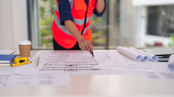 Профессиональный архитектор тщательно изучает сложные строительные планы. Ориентированные работы, необходимые для успешного выполнения проекта и точного развития строительства.