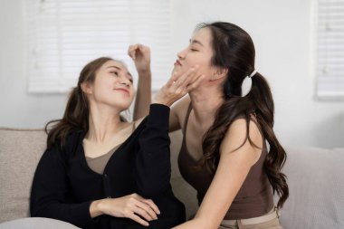 Yetişkin Asyalı lezbiyen çift sıcak bir ortamda sevgi ve mutluluk ifade ederek evlerinde samimi bir an paylaşıyorlar.