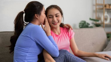 Yetişkin Asyalı kadınlar kanepede sıkı fıkı olurlar. Özel konuşmalar. Arkadaşlık bağı ve evde rahatlama havası.