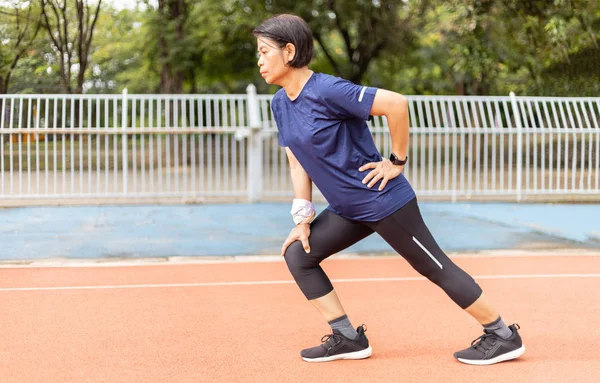 asia middle age women stretching her leg after jogging