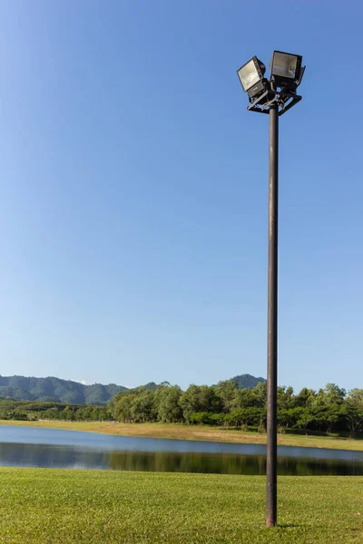 黑色后花园灯与湖泊和森林和蓝天背景 图库图片