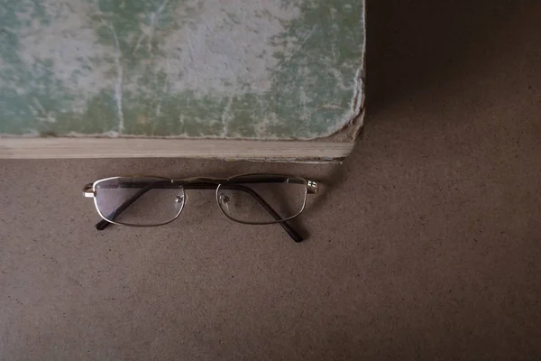 Brýle u staré knihy s potrhané hrany a ošuntělé víko. Koncept čtení a vzdělání. Pohled shora, místo kopírování — Stock fotografie