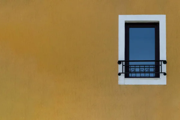 Window on the yellow building facade in Bulgaria, closed window in the street. Modern house window with a mini wrought iron balcony. Minimal composition. Place fot text. Casement wallpaper concept — Stock Photo, Image
