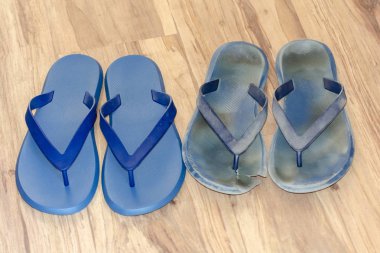 Açık kahverengi zemin üzerinde yeni ve eski kirli parmak arası terlik. İki çift yeni ve yıpranmış ayakkabılar. Ahşap arka planda izole edilmiş mavi sandaletler. Kavram öncesi ve sonrası