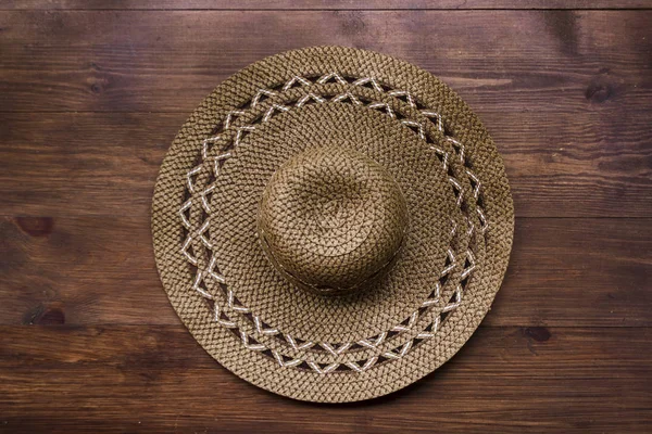 木製の背景に茶色の素朴なわら帽子のトップビュー。夏休みの田舎のコンセプト。女性と男性のアクセサリーのクローズアップは、夏休みに旅行する予定です。テキスト用のスペース ロイヤリティフリーのストック画像