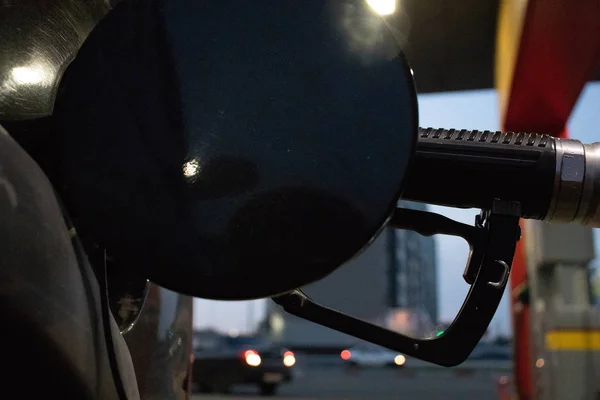 close-up fueling gun in a car tank against the background of the city at a gas station