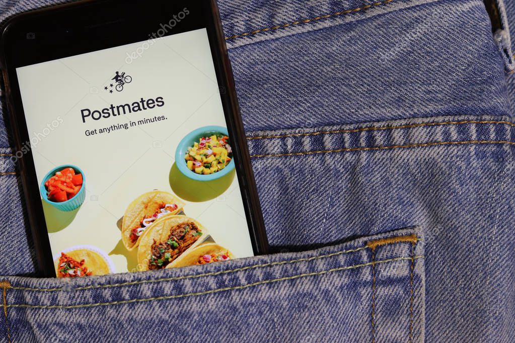 Los Angeles, California, USA - 10 October 2019:  Mobile phone with Postmates logo on screen close up in the blue jeans pocket, Illustrative Editorial