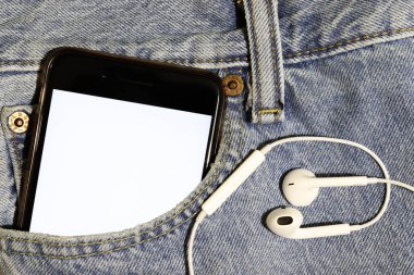 Görsel-işitsel içerik şablonu. Bir podcast veya şarkı illüstrasyonu eklenecek yer. Beyaz ekranlı akıllı telefon ve mavi kot pantolon cebinde kulaklıklar..