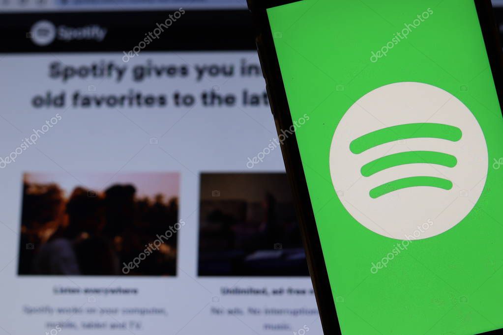 Mobile phone with Spotify logo on screen close up with website on laptop. Blurred background with Spotify. Los Angeles, California, USA - 27 October 2019, Illustrative Editorial