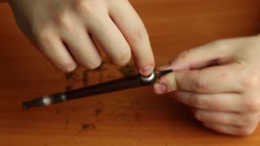 Elleri olan bir adam pipoya tütün koyar ve kamerada gösterir. Sigara piposu tıkanıyor..