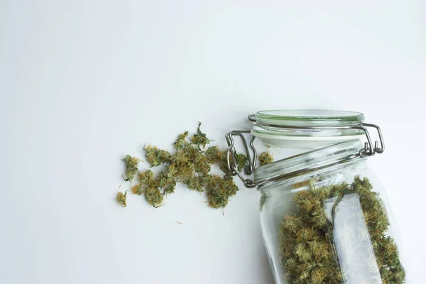 Open jar with cannabis on white background with copy space. Marijuana concept.