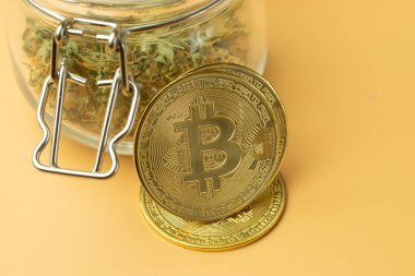 İsimsiz olarak uyuşturucu almak için Bitcoin kripto para birimi kullanılıyor. BTC madeni para için marihuana alımı. Turuncu arkaplan yakın plan.