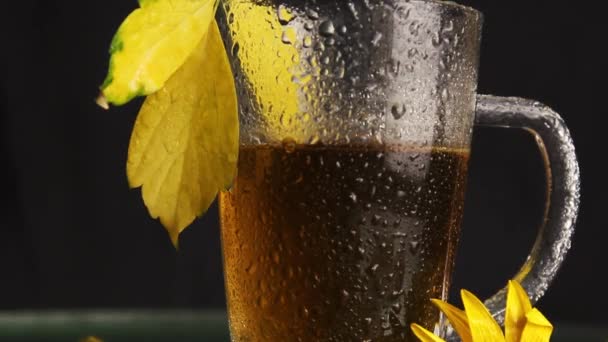 秋の風景の真っ只中に熱いお茶の雨が立った後 透明なガラスのマグカップが濡れています 黄色の落ち葉 黄色の花 秋の気分 — ストック動画