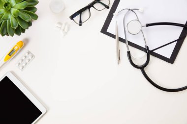Tablet bilgisayar tarafından termometre ve beyaz üzerinde tıbbi araçlar 