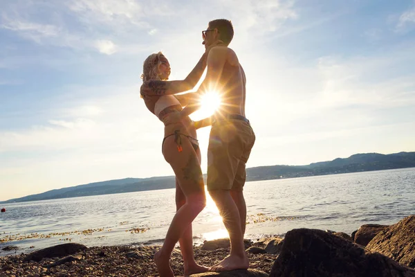 Couple amoureux s'embrassent sur la plage contre le soleil — Photo