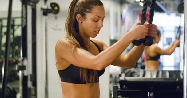 Сосредоточенная женщина тренирует мышцы трицепса дергая кабельную машину в тренажерном зале — стоковое видео