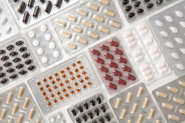 Comprimidos coloridos em embalagens de blister na mesa — Fotografia de Stock