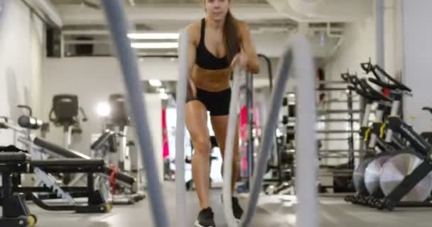 Entrenamiento de intervalo de alta intensidad femenino atlético con cuerdas de batalla — Vídeo de stock