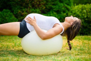 Yoga topu germe arkasında hamile kadın, gözleri kapalı