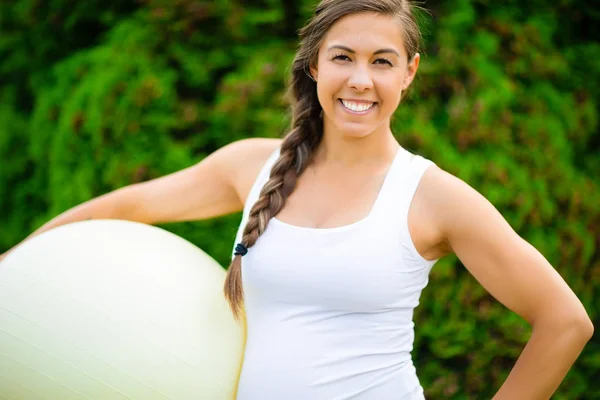 Sourire jeune femme enceinte tenant balle de remise en forme dans le parc — Photo