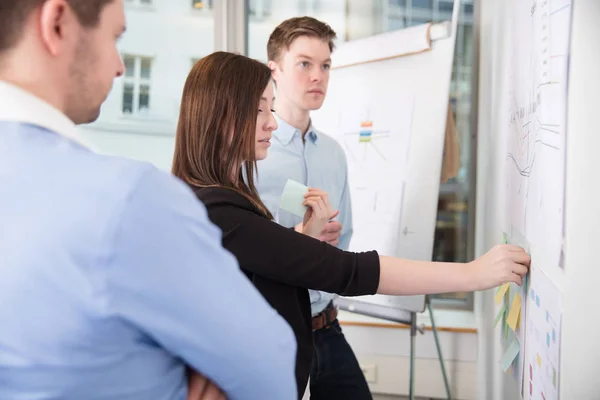 Businesswoman Sticking Notes While Standing By Male Colleagues — Stock Photo, Image