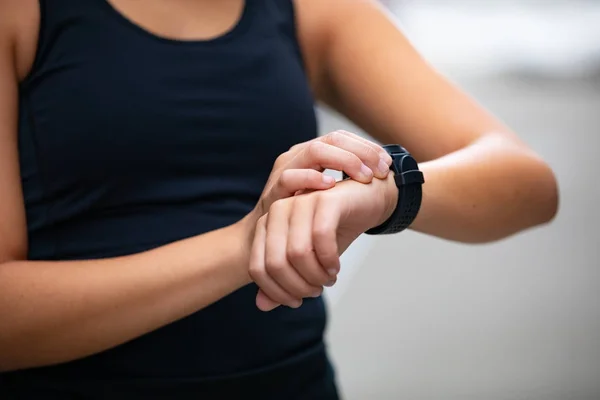 Primer plano de la mujer que utiliza el dispositivo de reloj inteligente fitness antes de correr —  Fotos de Stock