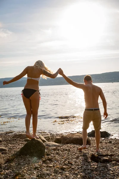 Couple amoureux se tenant la main à la plage contre le soleil — Photo